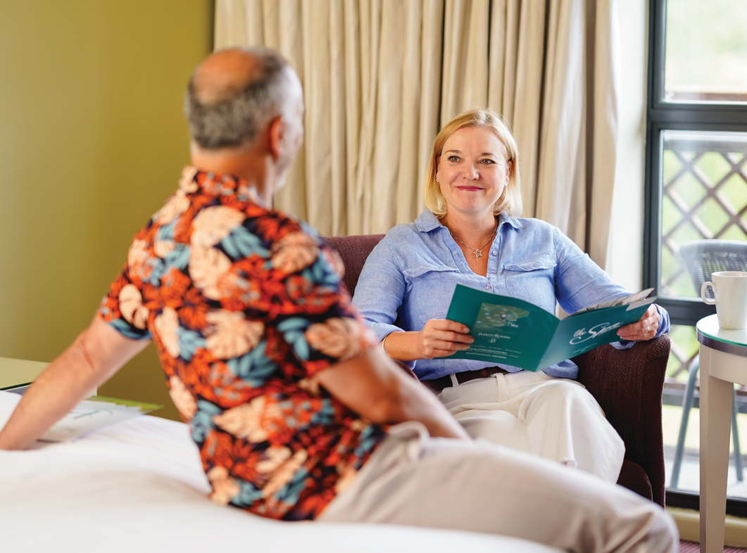Models relaxing in their Potters Resort room reading resort activities brochure